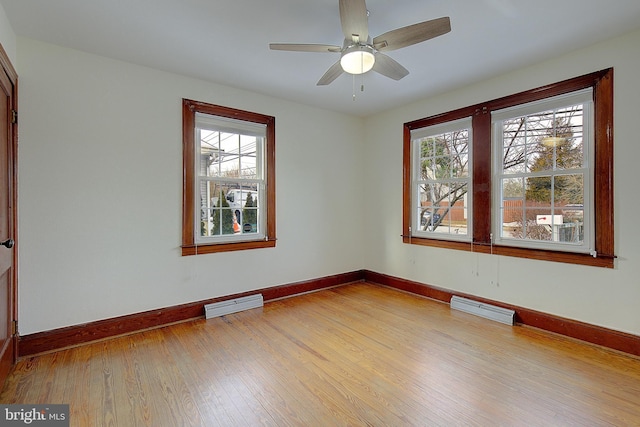 empty room with plenty of natural light, ceiling fan, and light hardwood / wood-style flooring