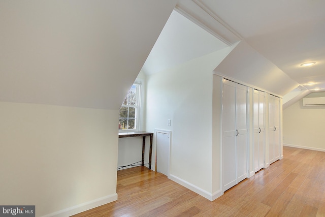 bonus room with lofted ceiling, a wall mounted air conditioner, and light hardwood / wood-style floors