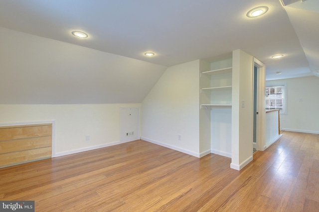 bonus room featuring lofted ceiling, built in features, and light wood-type flooring