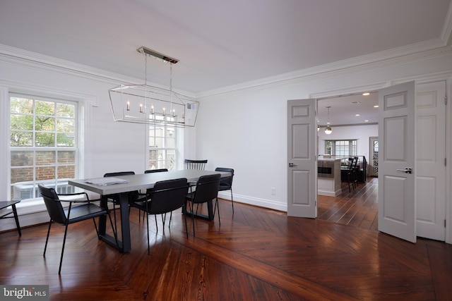 dining space with dark parquet flooring, crown molding, and a notable chandelier