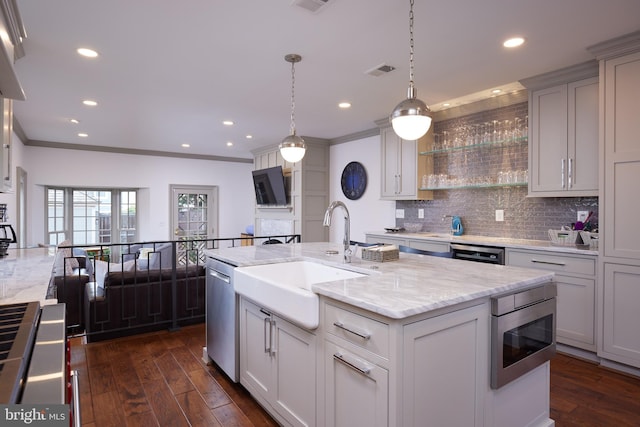 kitchen with a kitchen island with sink, sink, dark wood-type flooring, pendant lighting, and stainless steel appliances