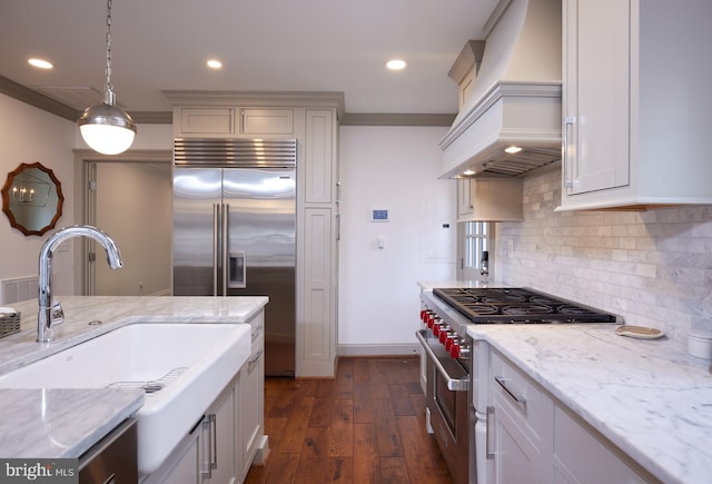 kitchen with custom exhaust hood, hanging light fixtures, premium appliances, and light stone countertops