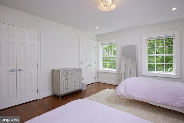 bedroom featuring an inviting chandelier, dark hardwood / wood-style flooring, and multiple windows