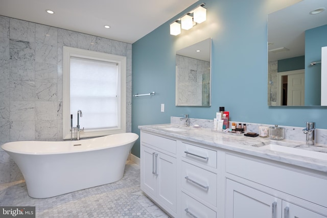 bathroom with a bath, tile patterned floors, tile walls, and vanity