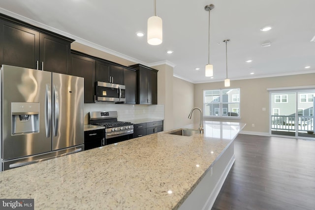 kitchen featuring sink, appliances with stainless steel finishes, plenty of natural light, light stone counters, and decorative light fixtures