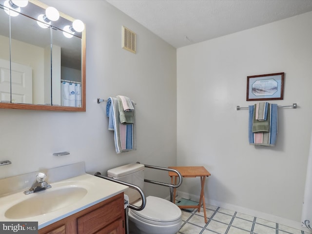 bathroom featuring vanity, toilet, tile patterned flooring, and a textured ceiling