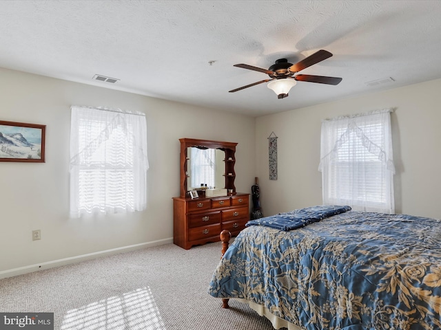 bedroom featuring light colored carpet, a textured ceiling, and ceiling fan