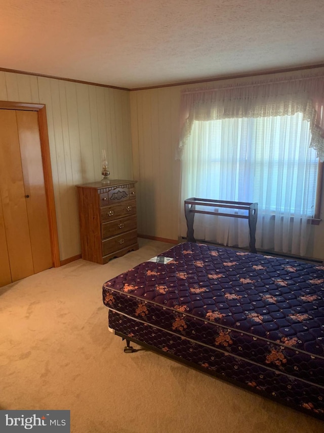 unfurnished bedroom with a textured ceiling, carpet floors, and wooden walls