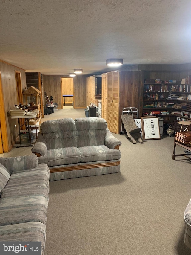 carpeted living room featuring wood walls and a textured ceiling