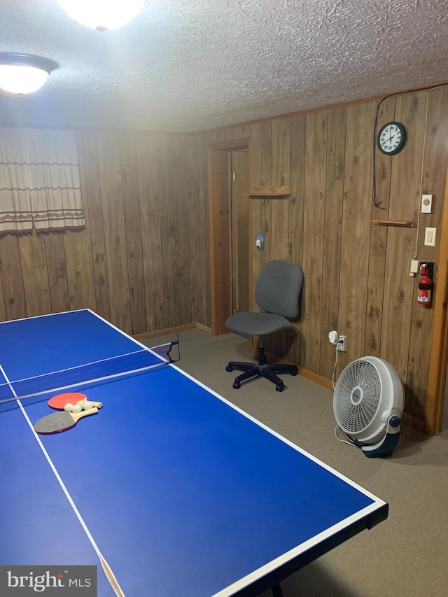 playroom featuring wood walls, a textured ceiling, and carpet flooring