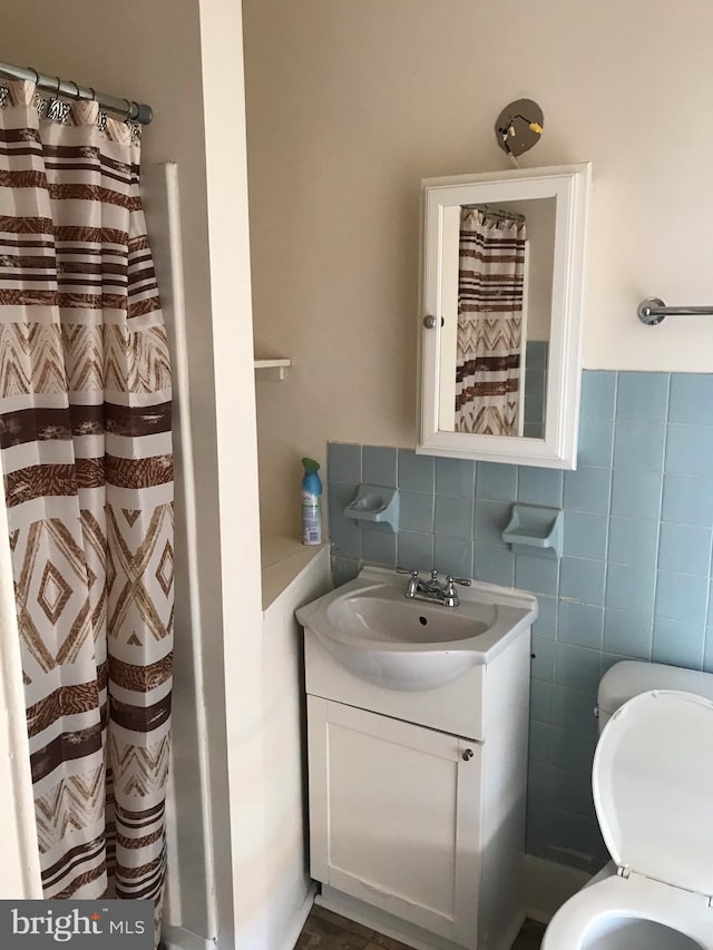 bathroom featuring vanity, walk in shower, and tile walls