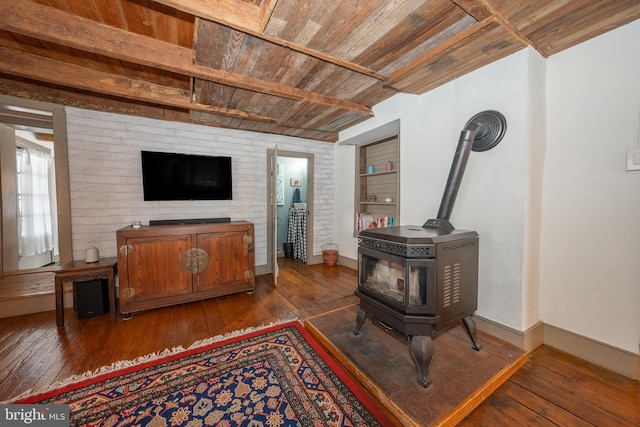 living room with beamed ceiling, a wood stove, dark wood-type flooring, and wooden ceiling