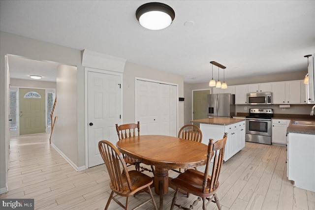 dining area with sink and light wood-type flooring