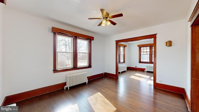 spare room with dark hardwood / wood-style flooring, radiator heating unit, and a healthy amount of sunlight