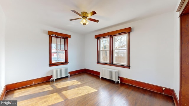 unfurnished room with radiator heating unit, wood-type flooring, and a wealth of natural light