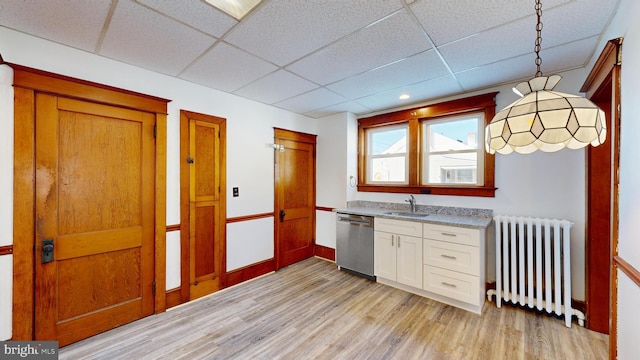 kitchen featuring sink, decorative light fixtures, radiator heating unit, dishwasher, and white cabinets