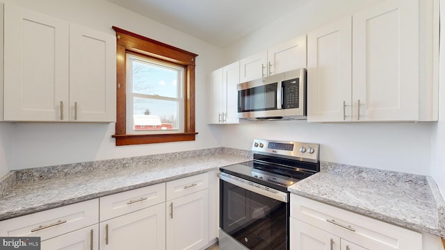 kitchen with light stone countertops, appliances with stainless steel finishes, and white cabinets