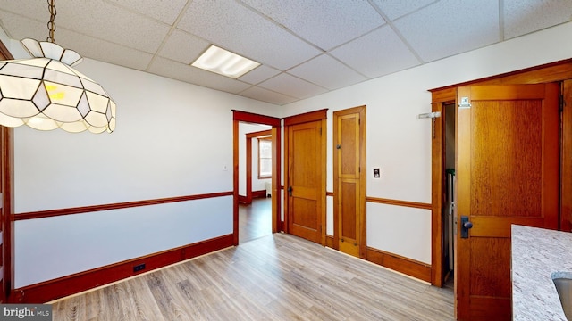 spare room featuring a drop ceiling and light hardwood / wood-style floors