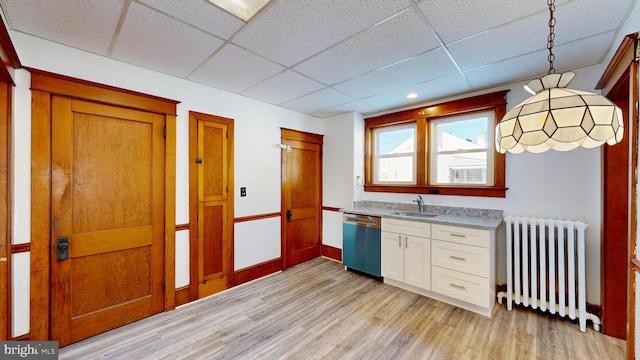 kitchen featuring radiator, sink, white cabinetry, decorative light fixtures, and stainless steel dishwasher