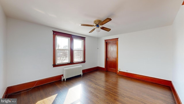 spare room featuring radiator, dark wood-type flooring, and ceiling fan