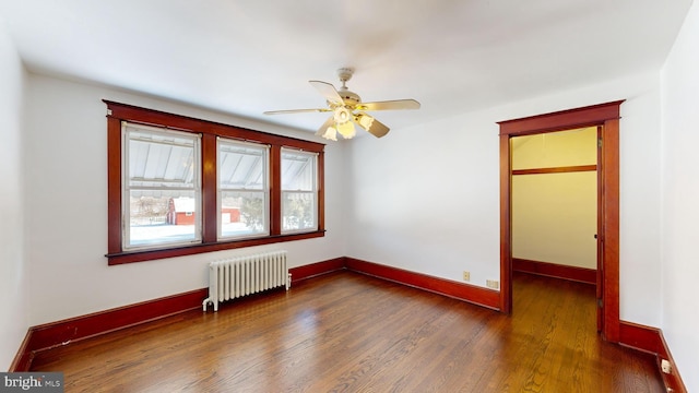 spare room featuring dark wood-type flooring, ceiling fan, and radiator