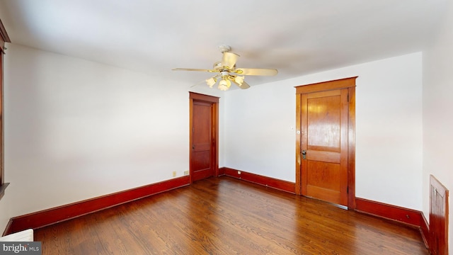 empty room with dark hardwood / wood-style floors and ceiling fan