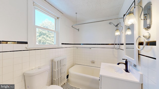 full bathroom with toilet, tile walls, a textured ceiling, radiator heating unit, and vanity