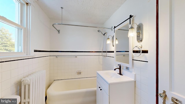 bathroom featuring radiator heating unit, vanity, a textured ceiling, and tile walls