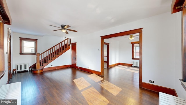 unfurnished room featuring dark wood-type flooring, ceiling fan, and radiator