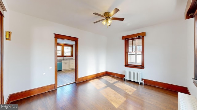 unfurnished room with ceiling fan, radiator heating unit, and wood-type flooring