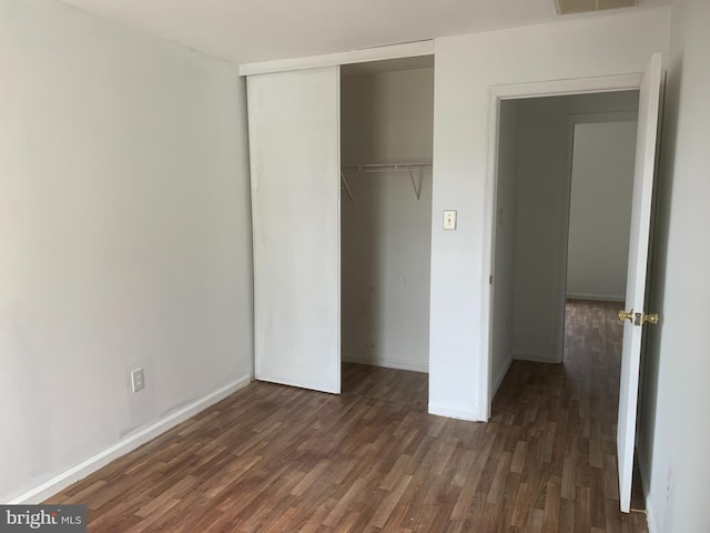 unfurnished bedroom featuring a closet and dark hardwood / wood-style flooring