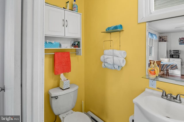 bathroom featuring baseboard heating, toilet, and sink