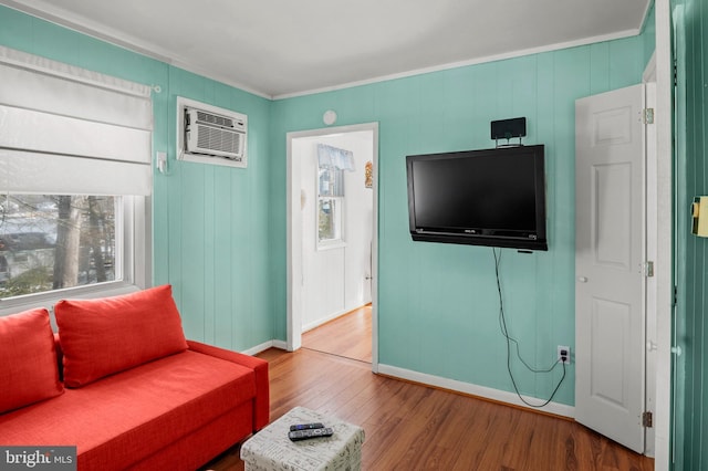 living room featuring a wall mounted air conditioner, hardwood / wood-style flooring, and ornamental molding