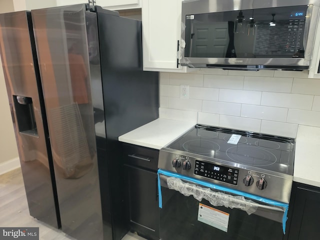 kitchen featuring tasteful backsplash, appliances with stainless steel finishes, white cabinets, and light hardwood / wood-style floors