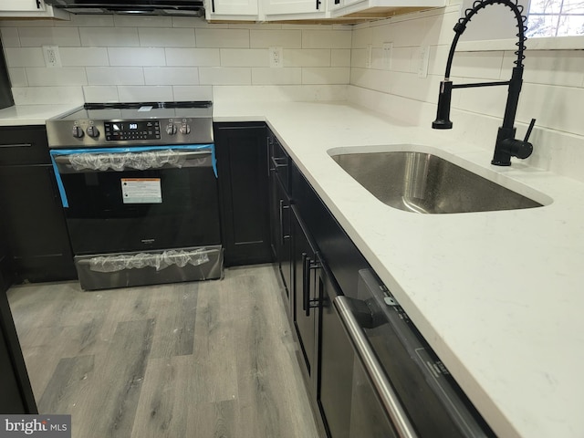 kitchen with sink, white cabinets, stainless steel range with electric cooktop, backsplash, and light hardwood / wood-style flooring