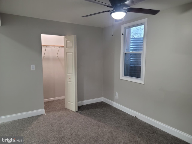 unfurnished bedroom with ceiling fan, a spacious closet, a closet, and carpet