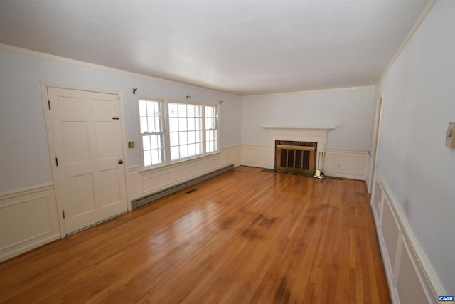 unfurnished living room with a brick fireplace, light wood-type flooring, a baseboard heating unit, and ornamental molding