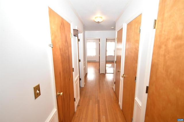 hallway featuring a baseboard radiator, light hardwood / wood-style floors, and ornamental molding