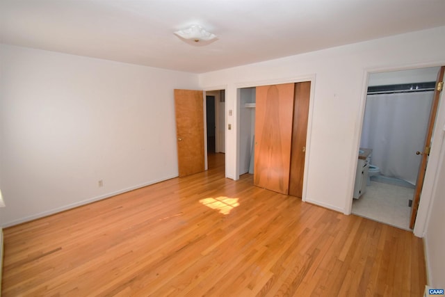 unfurnished bedroom with light hardwood / wood-style floors and two closets