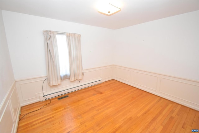 spare room featuring hardwood / wood-style floors and a baseboard radiator