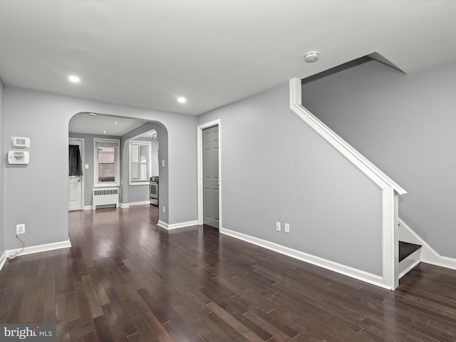 unfurnished living room featuring dark wood-type flooring and radiator