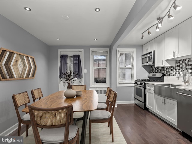 dining space with sink, track lighting, and dark hardwood / wood-style flooring