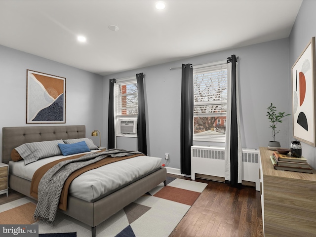 bedroom with cooling unit, radiator, and dark hardwood / wood-style floors