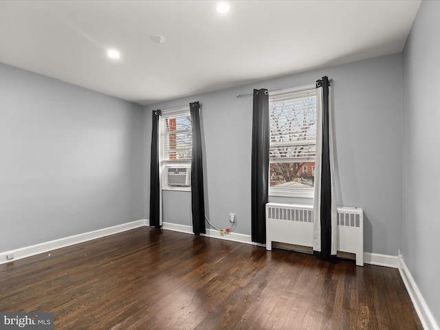 unfurnished room featuring dark hardwood / wood-style flooring, cooling unit, and radiator heating unit