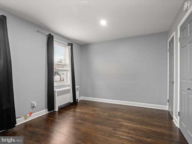 unfurnished room featuring radiator heating unit and dark hardwood / wood-style floors