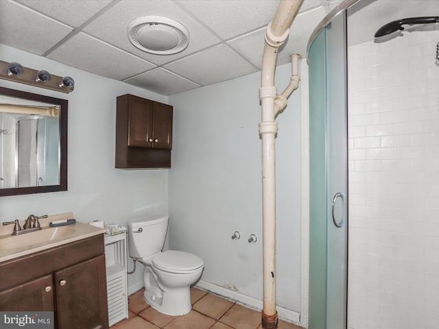 bathroom featuring toilet, vanity, a shower with door, tile patterned flooring, and a drop ceiling