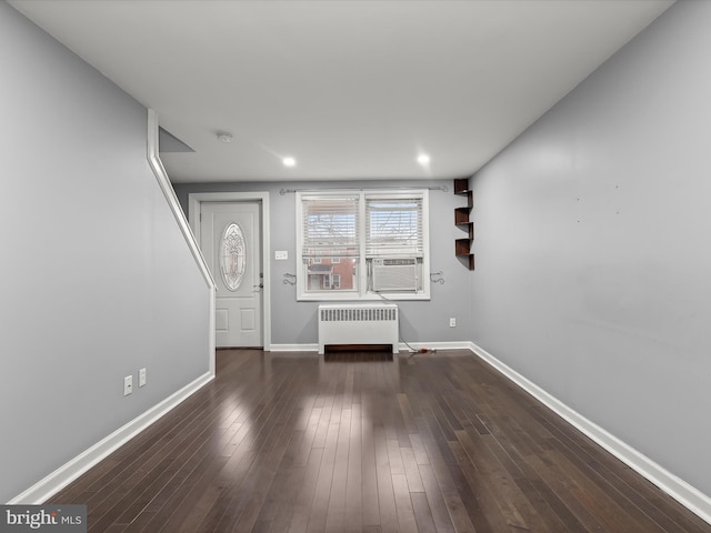 unfurnished living room with cooling unit, dark hardwood / wood-style flooring, and radiator