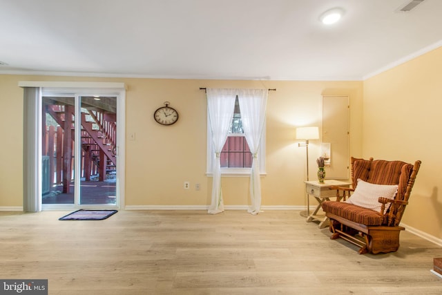 sitting room featuring ornamental molding and light wood-type flooring