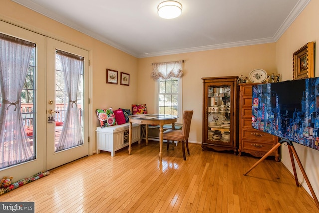 dining space featuring french doors, crown molding, and light hardwood / wood-style flooring