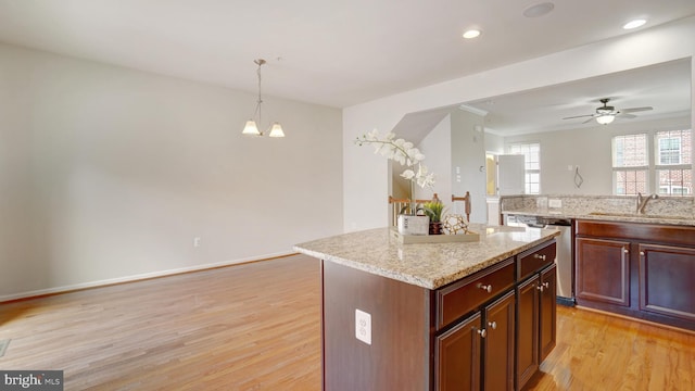 kitchen with sink, dishwasher, hanging light fixtures, a kitchen island, and light wood-type flooring